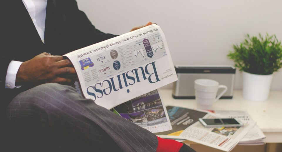 person sitting near table holding newspaper