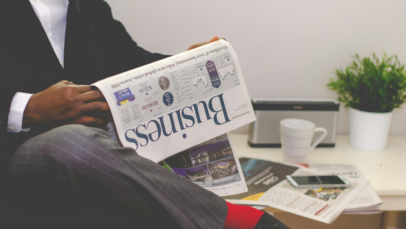 person sitting near table holding newspaper